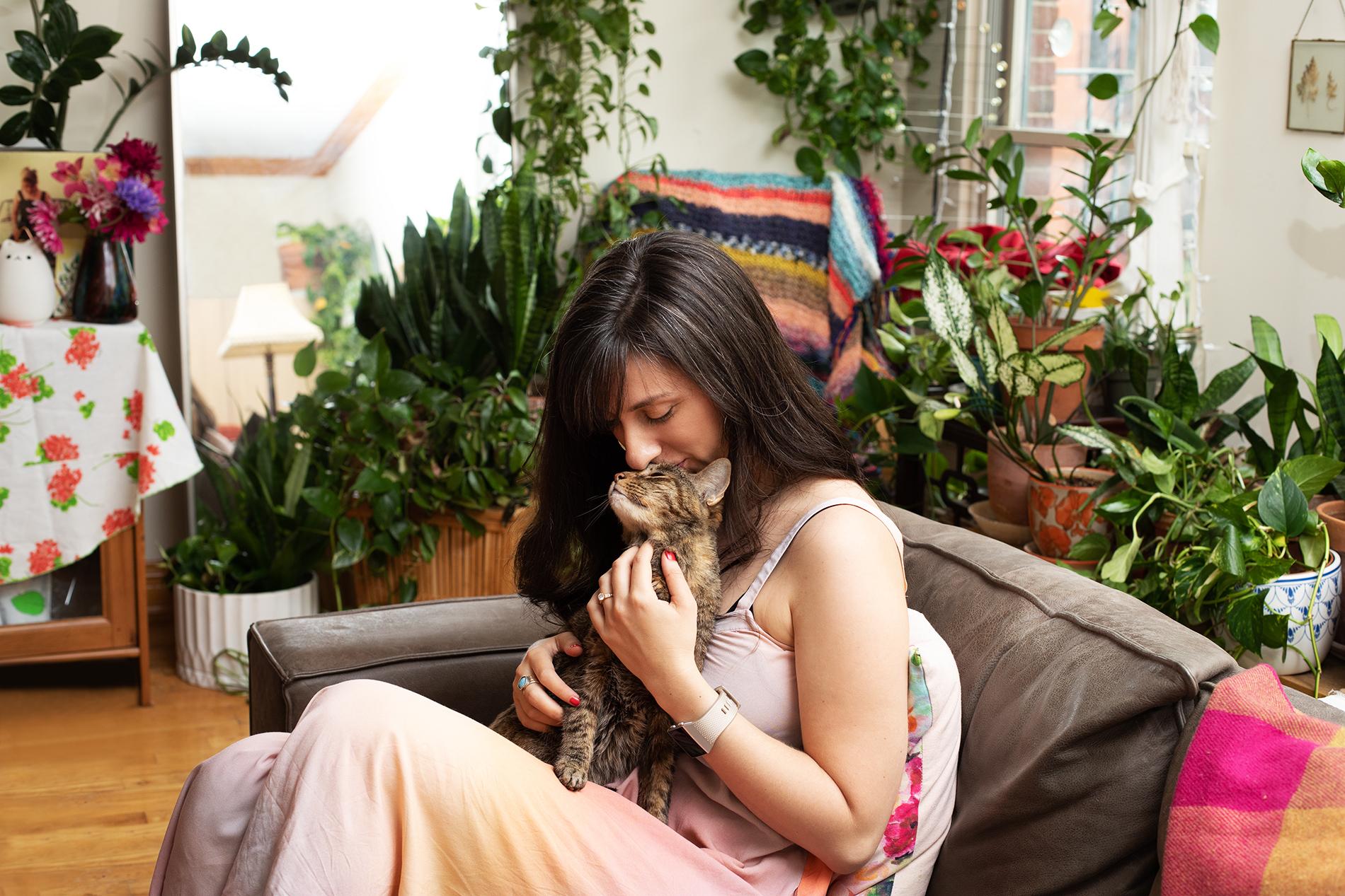 Paige Rechtman, pet loss therapist, cuddling her kitten on a couch